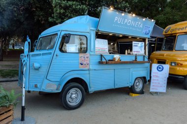 Barselona, İspanya - 24 Ekim 2023: Fast food satışına hazır Retro van. Parktaki bir etkinlikte yemek kamyonu..