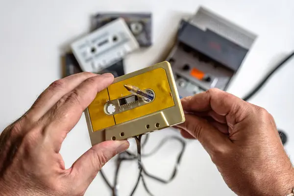 Beyaz arkaplanda bir kalem, kaset çalar ve birkaç kaset yardımıyla bir kaseti elle geri sarma.