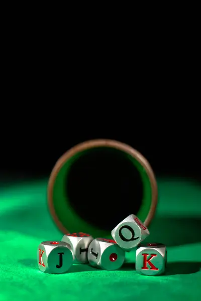 Poker dice in a cup on a vibrant green mat with copy space. Capture the intrigue and suspense of a game in full development