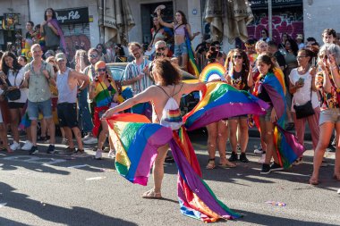 Barselona, İspanya - 15 Temmuz 2023: Barcelona gay geçit töreni sırasında gökkuşağı eteği giyen bir adam. Sahne, etkinlik sırasında LGBTQ topluluğunun neşeli ruhunu gösteriyor..