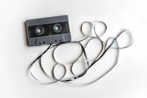Karışık kaset beyaz bir yüzeye dökülüyor. Müziğin geçmiş çağını temsil eden nostaljik bir görüntü..