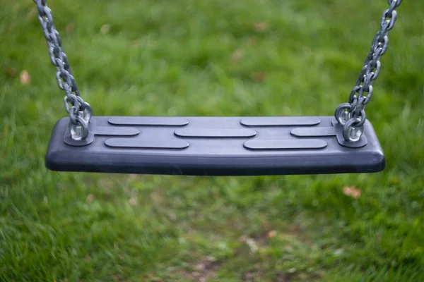 stock image Empty black swing detail on playground with vintage lens blurred bokeh grass on background