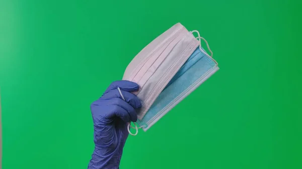 女用手拿着乳胶蓝色手套 戴着蓝白相间的医用防护面具 医生手戴防护手套 表现出对结肠癌病毒的防护 在绿屏背景下的特写 — 图库照片