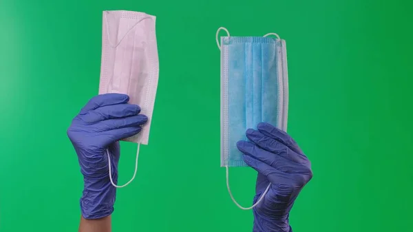 戴乳胶蓝色手套的女手戴着蓝白相间的医用防护面具 戴防护手套的医生手臂表现出对结肠癌病毒的保护 在绿屏背景下的特写 — 图库照片