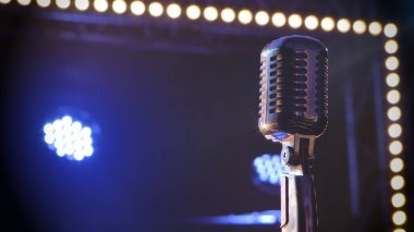 Profesyonel konser klasiği parlayan mikrofon. Kayıt için mikrofon kullanın ya da boş bir retro kulübünde sahnede seyircilerle konuşun. Mavi spot ışıkları ve stüdyo ışıklarıyla dumanlı bir arka planda çekilmiş.