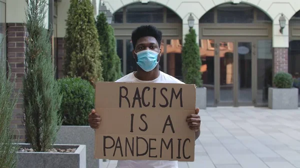 Młody Afroamerykanin Masce Medycznej Stoi Tekturowym Plakatem Racism Pandemic Publicznym — Zdjęcie stockowe