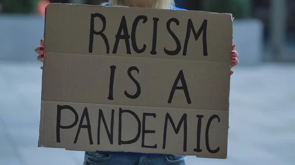 Racismは 女性抗議活動家の手による段ボールポスターのPandemicです 人種差別をやめろ人種差別はしない 人種差別や警察の残虐行為に反対する 黒人の平和的な生活は重要である — ストック写真