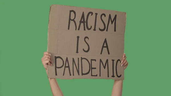 Hands of women raising up cardboard poster RACISM IS A PANDEMIC. Stop Racism concept, No Racism. Rallies against racism and discrimination. Peaceful life of blacks matters. Isolated green screen
