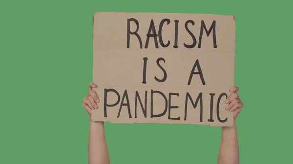 Hands of men raising up cardboard poster RACISM IS A PANDEMIC. Stop Racism concept, No Racism. Rallies against racism and discrimination. Peaceful life of blacks matters. Isolated green screen chroma