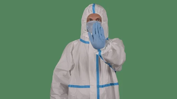 白い保護服を着た医療従事者やウイルス学者 手のひらでStopジェスチャーを示す医療用マスク 危険な警告のジェスチャーをする男 ウイルスCovid 19流行概念 緑の画面 — ストック写真