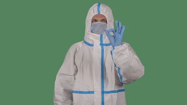 白い保護スーツの医療従事者やウイルス学者や指のジェスチャーOkを示す医療マスク ウイルスCovid 19流行概念 緑の画面 — ストック写真