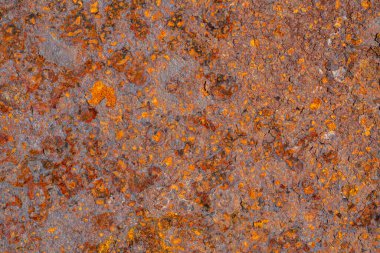 Demir pas dokusu arka planda. Metal paslı arka plan, çürümüş çelik, çizik ve çatlakla metal doku. Sarı ve turuncu aşınma desenli paslı kahverengi metal bir levhanın makro görüntüsü.