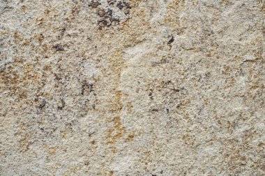 Duvar, beyaz, gri ve kahverengi lekeli dekoratif mermer kırıntılarıyla kaplı. Ön cephesinde pas lekeleri olan mermer alçılı eve bakıyor. Yapı mermer parçacıklarının makro çekimi, beton