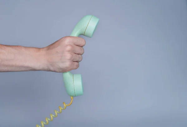 灰色の背景に古い青のプラスチック製の電話受信機を保持男性の手 男の手にレトロなロータリーホーム電話からリモート携帯電話を閉じます コミュニケーション 会話の概念 — ストック写真