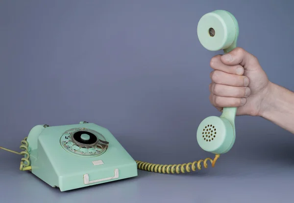 Мужчина Держит Старую Синюю Пластиковую Телефонную Трубку Возле Ротационного Телефона — стоковое фото