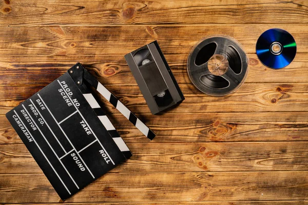 电影胶片盒 黑色塑料Vhs盒带和拍板的褐色木制背景 旧的存储介质 用于观看视频或电影或听音乐的驱动器 — 图库照片