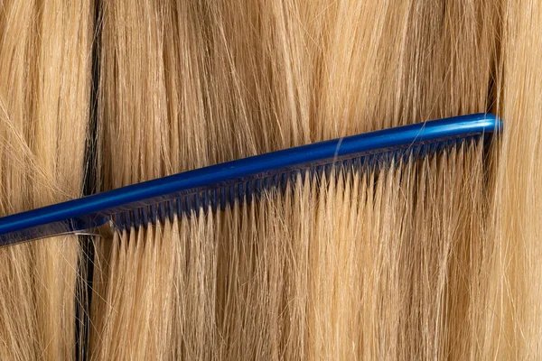 ブロンドの滑らかな女性の髪を組み合わせたマクロショット 髪の長い健康的な鎖を組み合わせた頻繁に細かい歯を持つ青い櫛の詳細ビュー サロン 理容室 美容室のためのフレーム ヘアケア — ストック写真