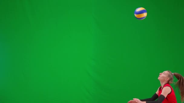 年轻的女排选手在绿屏上跳着击球 身穿红色制服的女运动员用手触球 排球赛 把球投进比赛中 为球员服务 — 图库视频影像