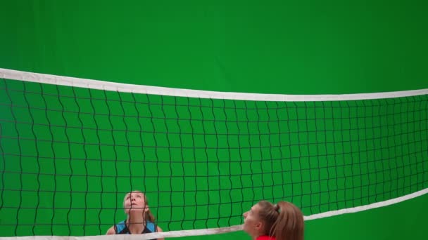 緑色の画面のクロマキーでバレーボールをしているスポーツウェアの2人の若い女性 女子アスリートはゴールと喜びを決め 相手はボールを逃して動揺する 攻撃力と防御力の練習 — ストック動画