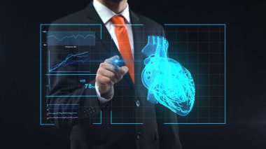 Siyah elbiseli adam teknolojik medikal monitörde dokunmatik ekranla parmak holografik arayüzü ile dokunuyor. Doktor kalp ile sanal holograma bakıyor. Teşhis, tedavi, araştırma