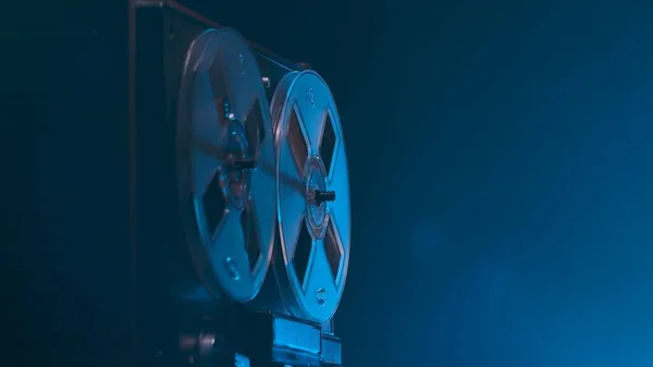 在带蓝光的工作室背景上旋转卷轴录音机 具有磁带卷轴的模拟古董唱机 用于播放音乐 黑暗中的旧圆筒 复古派对 — 图库照片