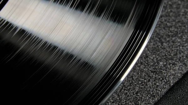 宏观拍摄的黑色光滑的凹凸不平的乙烯记录 一种由光照亮的发亮的旧留声机唱片 老式乙烯唱机 带乙烯转炉的复古背景 — 图库照片
