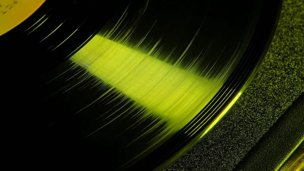 宏观拍摄的黑色光泽乙烯记录与槽 黄色的光照亮了一张发亮的旧留声机唱片 老式乙烯唱机 复古风格的音乐迪斯科晚会 复古背景 — 图库照片