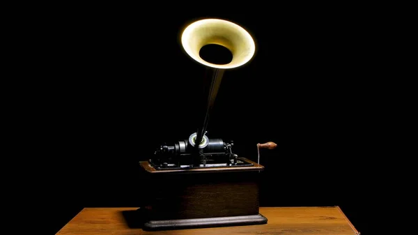 Classic Edison Phonograph on a wooden table in a dark studio. Retro vintage machine to reproduce sound making listening to music. Antique musical instrument with loudspeaker trumpet and a rotary