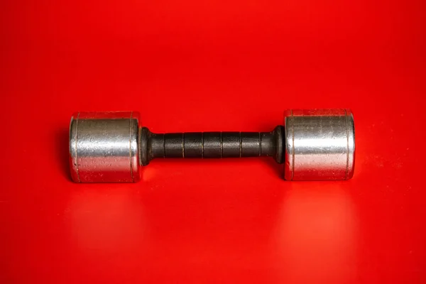一个银白色的哑铃躺在红色的背景上 用于抽吸肌肉的哑铃 健美等方面的运动器材 健康生活方式 运动和力量训练的概念 — 图库照片