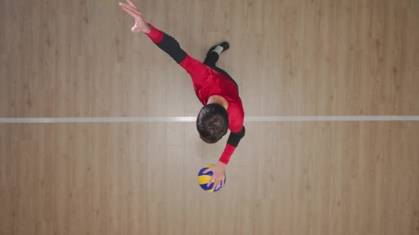 木製の床にボールを打つ若い男のトップビュー 投げとジャンプでボールを打つ 男子アスリートは競技前にボールを提供するスキルを発揮します バレーボールコートのアスリート列車 — ストック動画