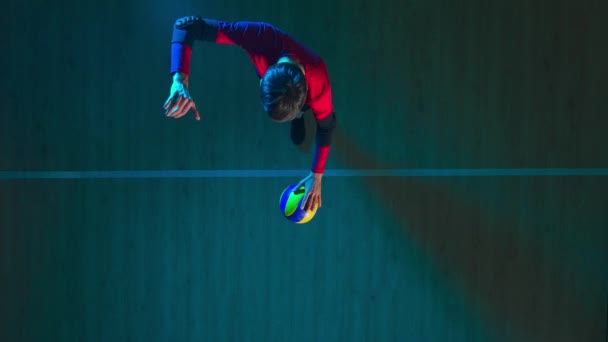 一个年轻人在木制地板上击球 在跳跃中抛掷和击球的倒影 男子运动员在蓝光下练习在排球场上发球的技巧 活动的概念 — 图库视频影像