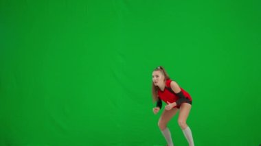 Spor heyecanı içinde genç bir kadın voleybol maçında topun servis edilmesini bekliyor. Atlet bayan voleybol oyuncusu hoplayıp zıplıyor, topa vuruyor ve yeşil ekran kroma tuşuna basıyor.