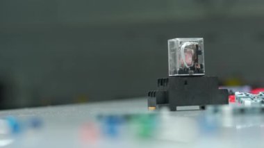 Elektrikçi, masa rölesine elektromanyetik bobinler ve alternatif akım serer. Elektirik atölyesinde otomatik elektrik düğmeleri için ekipmanlı bir adamın ellerini kapatın.