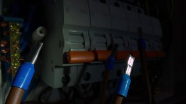 Karanlıkta fenerin ışığında mavi çalı gelinciği olan kahverengi kabloların makro görüntüsü. Santraldeki yüksek voltajlı elektrik düğmeleri. Otomatik sigortalı, kablolu, sarı düğmeli kutucuğu değiştir