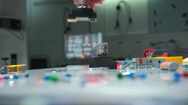 电工们躺在桌上 带着直流电和交流电的电磁线圈 红色和黄色灯泡 感应器 用自动电气设备把一个人的手拉紧 — 图库视频影像