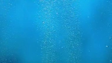 Suyun altından yüzeye yükselen parlak hava kabarcıkları ve ışık ışınlarıyla aydınlanıyor. Mavi okyanusta ya da deniz suyunda oksijen kabarcıkları. Havalandırma sırasında kaynayan bir sıvıyı kapat