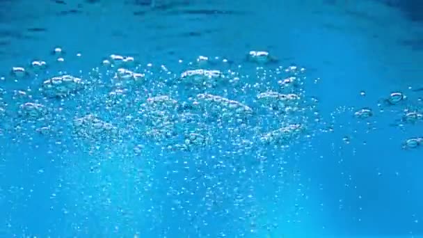 深さから青い水の表面に上昇する気泡の流れ 液体の表面に現れる酸素泡の閉じ込めと破裂 水の泡 炭素化 — ストック動画