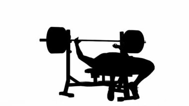 Siyah siluet, kaslı bir adam spor bankında yatıyor ve geniş disk ağırlıklarıyla halteri kaldırıyor. Vücut geliştirici parmaklar, trisepsler, göğüs ve deltoid kas için egzersiz yapıyor. Güç kaldırma ya da geçiş