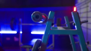 Halterli metal askı ya da bulanık spor arka planında mavi ve kırmızı ışıklı çapraz çubuk. Boş, karanlık bir spor salonundaki gri tezgahı kapat. Spor malzemeleri, vücut geliştirme, fitness, Crossfit ve
