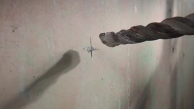 Elektrikli matkap ya da delgi kullanarak beton duvarda delik açma işlemi. Metal spiral matkabın kapağı dönüyor. Matkapla delme işlemi sırasında alçıdan çıkan beyaz toz ufalanır.