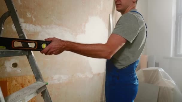 Man Blue Construction Overalls Takes Water Level Makes Marks Yellow — Stock Video