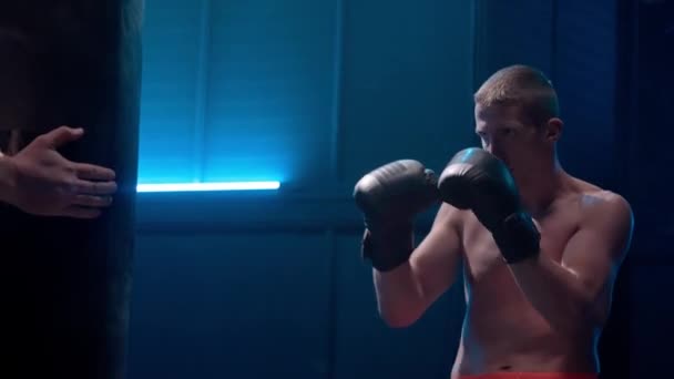 Young Male Kickboxer Boxing Gloves Punching Kicking Legs Punchbag Dark — Stock Video