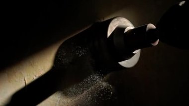 Karanlıkta ışık huzmesi ile duvarda delik açmak için makro atış. Elektrikli matkap veya delgi üzerinde dönen metal yuvarlak başlık. Beyaz tozu delme işlemi sırasında,