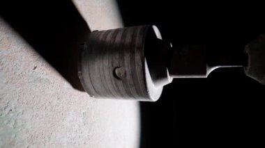 Beyaz duvarda delik açmak için makro atış. Elektrikli matkap veya döner delgi üzerinde dönen metal, yuvarlak bir kapağın yan görüntüsü. Sondaj işlemi sırasında alçıdan çıkan beyaz toz
