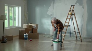 Tired grandpa entering the room and grandson merrily jumping out from behind stack of cardboard boxes. Young teenager is scaring an older man and together they laugh merrily at a joke. Concept of