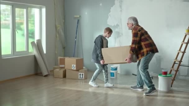 Grandpa Grandson Carrying Heavy Cardboard Box Placing Floor Window Elderly — Αρχείο Βίντεο