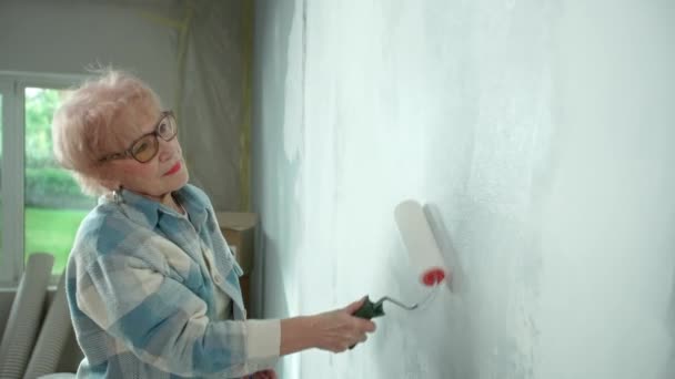 Starší Žena Maluje Stěnu Bílou Barvou Pomocí Válečku Žena Důchodkyně — Stock video