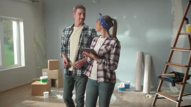 Happy Young Couple Checkered Shirts Using Tablet Plan Renovations Apartment — Vídeos de Stock