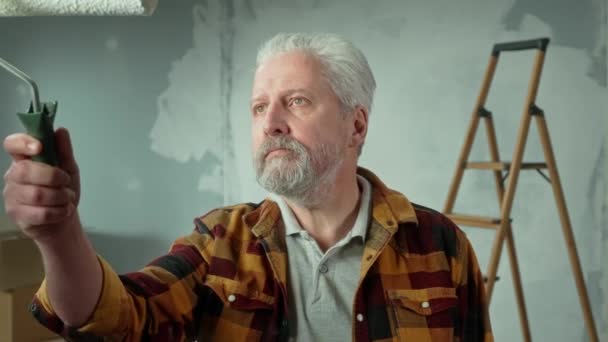 Elderly Man Painting Glass White Paint Using Roller Gray Haired — Stockvideo