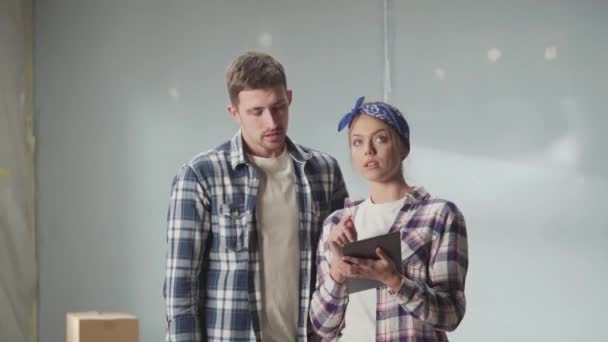Happy Young Couple Checkered Shirts Using Tablet Plan Renovations Apartment — Stockvideo